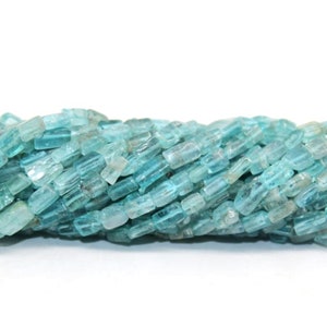 Könnte beinhalten: Eine Strähne aus hellblauen Aquamarin-Edelsteinkugeln. Die Perlen sind facettiert und haben eine rechteckige Form.