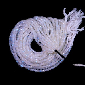 以下が含まれることがあります： 虹色の虹色の光沢を持つ白いムーンストーンビーズのストランド。ビーズはファセットカットされており、わずかに不規則な形をしています。ストランドは約40cmの長さで、黒い糸に糸で通されています。