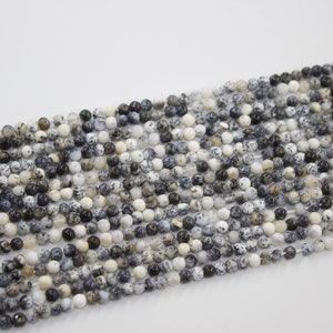 May include: A strand of round, white, black, and brown speckled beads. The beads are approximately 4mm in diameter and have a natural, polished finish.