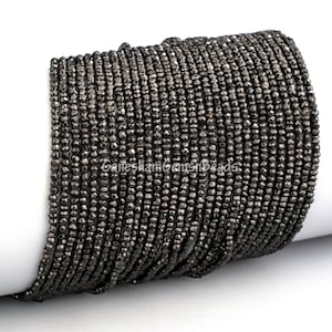 May include: A strand of black faceted gemstone beads. The beads are small and round, and they have a shiny, metallic finish.