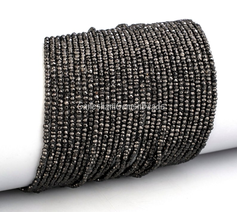 May include: A strand of black faceted gemstone beads. The beads are small and round, and they have a shiny, metallic finish.