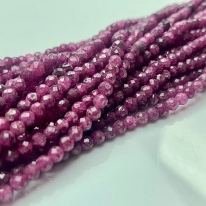 May include: A strand of faceted purple gemstone beads. The beads are small and round, and they have a smooth, polished finish.