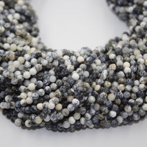May include: A strand of black and white speckled round beads. The beads are approximately 4mm in diameter and are made of natural stone.