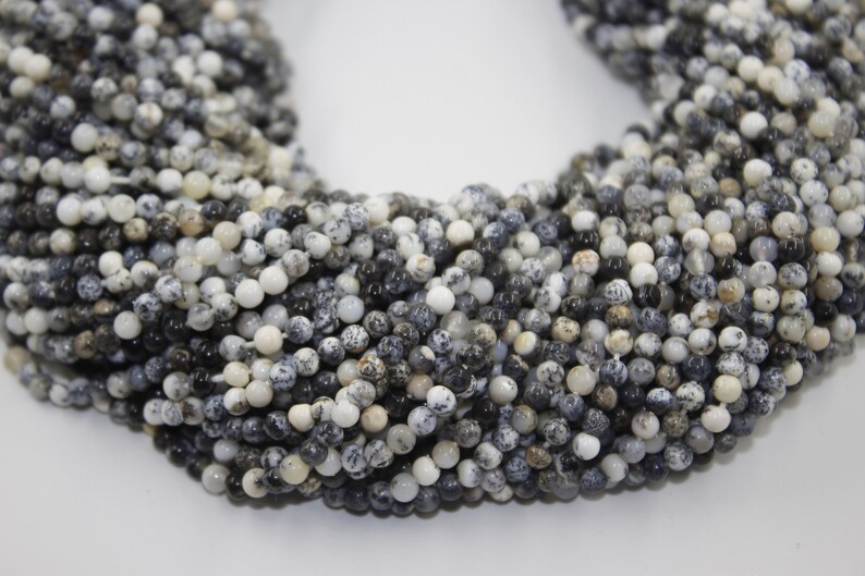 May include: A strand of black and white speckled round beads. The beads are approximately 4mm in diameter and are made of natural stone.