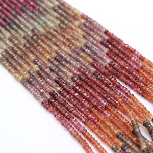 May include: A strand of faceted gemstone beads in shades of pink, red, orange, and brown. The beads are small and round, and they are strung on a clear thread.