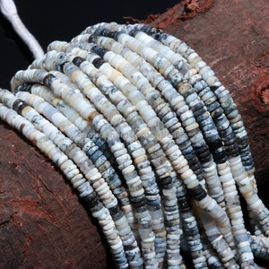 May include: A strand of white and gray opal beads. The beads are round and have a speckled pattern. The beads are strung on a white cord.