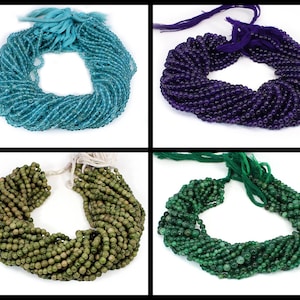 以下が含まれることがあります： 異なる色の丸い宝石ビーズが4本。ビーズは白い紐に通されています。色はターコイズ、パープル、グリーン、ダークグリーンです。