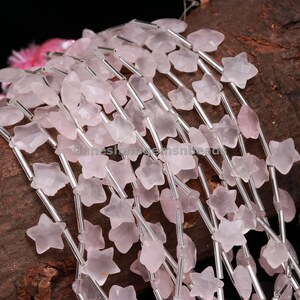 May include: A strand of pink star-shaped gemstone beads separated by silver spacer beads. The beads are strung on a silver wire.