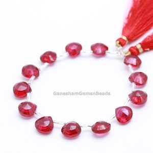 Könnte beinhalten: Eine Strähne aus 18 facettierten, herzförmigen, roten Edelsteinperlen. Die Perlen sind auf einem Silberdraht aufgefädelt und haben einen Durchmesser von etwa 10 mm. Die Strähne ist etwa 46 cm lang.  GaneshamGemsnBeads