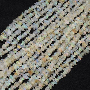May include: A strand of white opal chip beads. The beads are irregular in shape and have a translucent, iridescent quality.