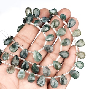 Könnte beinhalten: Eine Strähne grüner Moosachat-Edelsteinkugeln in Tropfenform. Die Perlen sind auf einem Silberdraht mit klaren Abstandshaltern aufgefädelt.