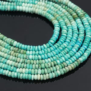 Peut inclure: Gros plan sur des brins de perles turquoise de différentes nuances de bleu-vert. Les perles sont petites, rondes et enfilées ensemble, créant une surface texturée. Les variations de couleur ajoutent de la profondeur et de l'intérêt visuel aux bijoux.