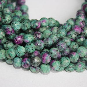 Op de afbeelding: Een streng groene en roze edelsteen kralen. De kralen zijn gefacetteerd en hebben een gevlekt uiterlijk.