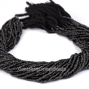 May include: A strand of black faceted glass beads. The beads are small and uniform in size. The strand is coiled into a circle.