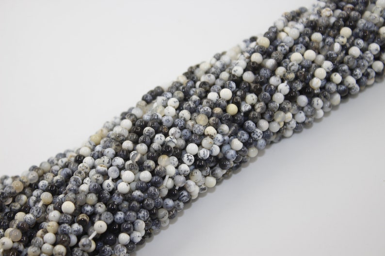 May include: A strand of black and white round gemstone beads. The beads are made of natural stone and have a speckled pattern.