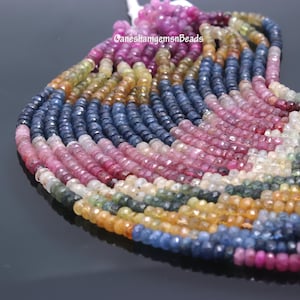 Könnte beinhalten: Eine Strähne aus mehrfarbigen Edelsteinperlen. Die Perlen sind facettiert und haben eine Vielzahl von Farben, darunter Blau, Rosa, Gelb und Grün. Die Perlen sind auf einem durchsichtigen Faden aufgefädelt und bereit für die Schmuckherstellung.