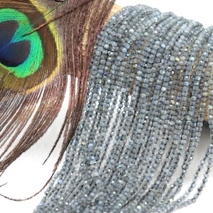 May include: A strand of gray faceted labradorite beads. The beads are small and round, and they have a slight iridescent sheen.