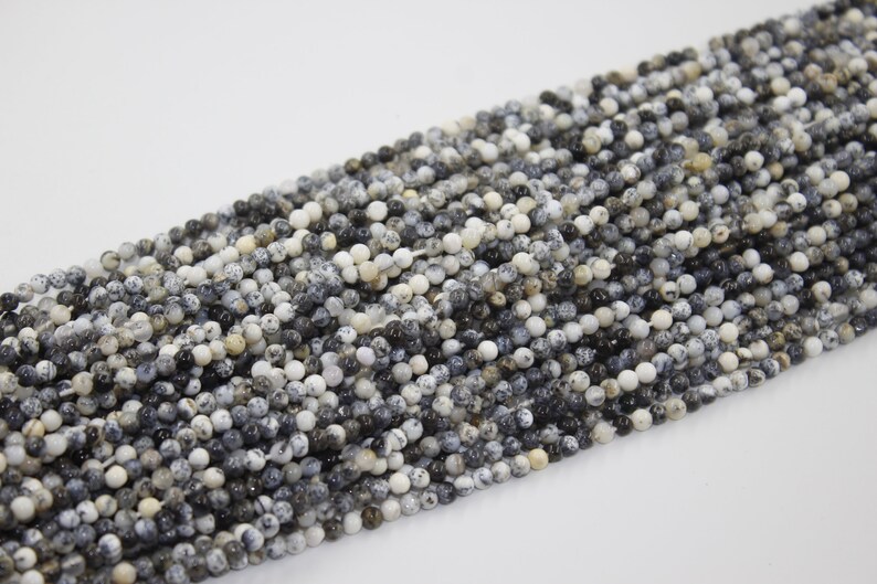 May include: A strand of black and white speckled round gemstone beads. The beads are approximately 4mm in diameter and have a natural, polished finish.