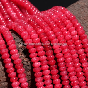 Könnte beinhalten: Eine Strähne aus leuchtend pinkfarbenen Edelsteinperlen. Die Perlen sind rund und haben eine leicht unregelmäßige Form. Sie sind auf einem durchsichtigen Faden aufgefädelt.