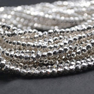 May include: Close-up of strands of faceted, silver-coloured beads. The beads have a metallic sheen and a multi-faceted surface, reflecting light. The beads are strung together, creating a textured and shiny appearance. Ideal for jewellery making.