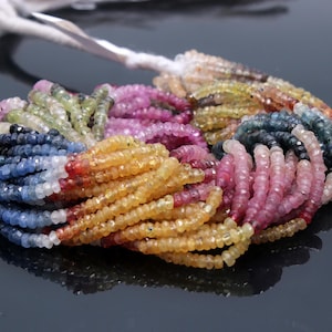 Puede incluir: Una hebra de cuentas de piedras preciosas facetadas en varios colores, incluyendo azul, rosa, amarillo y verde. Las cuentas son pequeñas y redondas, y están enhebradas en un cordón blanco.