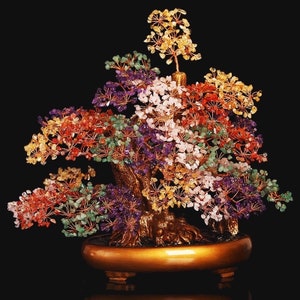 May include: A colorful crystal tree with a gold base. The tree is made of various gemstones, including amethyst, rose quartz, citrine, and green aventurine. The tree is a popular Feng Shui symbol for good luck and prosperity.