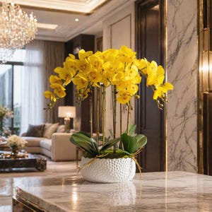 May include: A vibrant arrangement of yellow orchids in a white textured ceramic pot. The orchids have multiple stems and green leaves, creating a full and lush display. The pot sits on a marble surface, adding a touch of elegance to the floral arrangement.