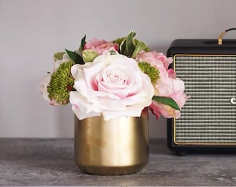 Puede incluir: Un ramo de rosas y peonías rosas en un jarrón dorado. Las flores están dispuestas en un estilo simple y elegante.