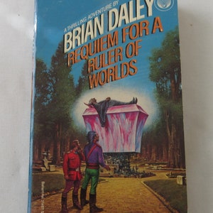 May include: A blue paperback book cover with the title "Requiem for a Ruler of Worlds" by Brian Daley. The cover features a colourful illustration of a person lying on a pink and blue platform.