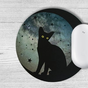 May include: A black cat silhouette with yellow eyes sits on a crescent moon against a starry night sky background. The moon and stars are a watercolour design on a round mouse mat.