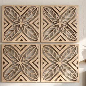May include: A set of four square light-colored wooden wall panels featuring a laser-cut design of symmetrical leaf patterns arranged in a cross shape, surrounded by geometric triangular corner accents, creating a cohesive grid display.