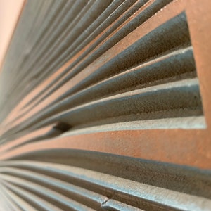 May include: Close-up of a textured, gray and brown wall panel with a curved, fan-like design.