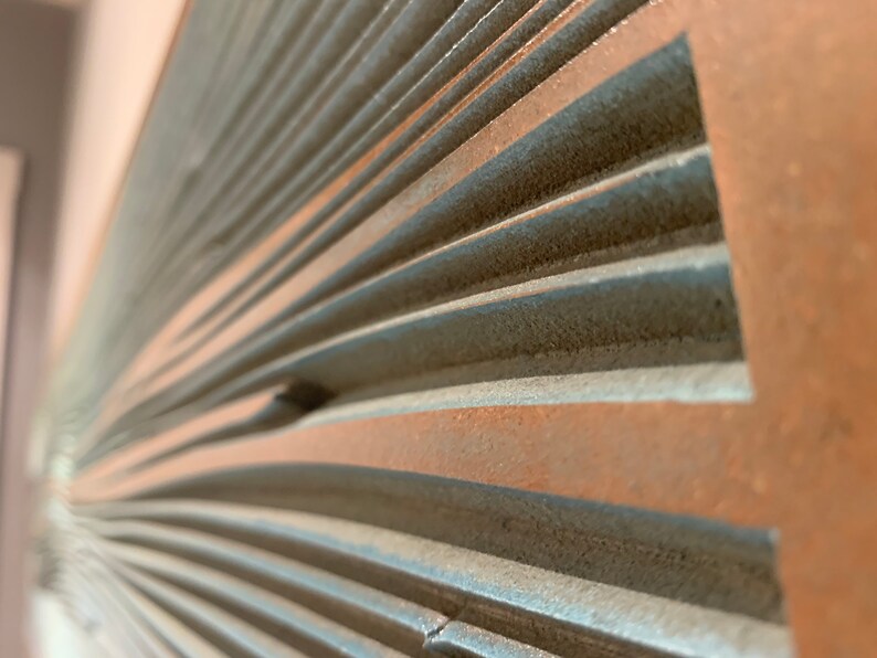May include: Close-up of a textured, gray and brown wall panel with a curved, fan-like design.