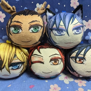 May include: Five plush round pillows with anime-style faces. The pillows are different colors and have different facial expressions. One pillow has antlers, one has cat ears, and one has a black eye patch.