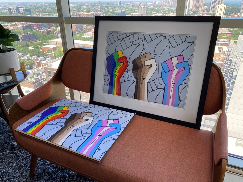 May include: Three raised fists with different colored stripes on their arms. The fists are raised in solidarity. The fists are on a white background with a gray pattern. The image is framed in black.