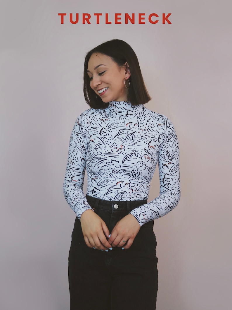 May include: A white turtleneck with a black and blue abstract print. The turtleneck is fitted and has long sleeves.