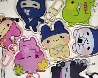 May include: A set of seven colorful character keychains. The keychains feature a variety of characters, including a ninja, a bunny, a frog, a bear, and a cat. Each keychain has a unique design and is made of clear acrylic.