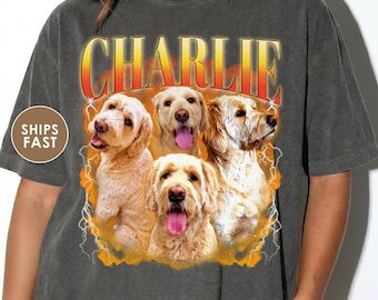 May include: Dark grey t-shirt with a graphic of four golden retriever-type dogs and the name "CHARLIE" in a retro font. The design has a vintage, distressed look with lightning bolt accents.