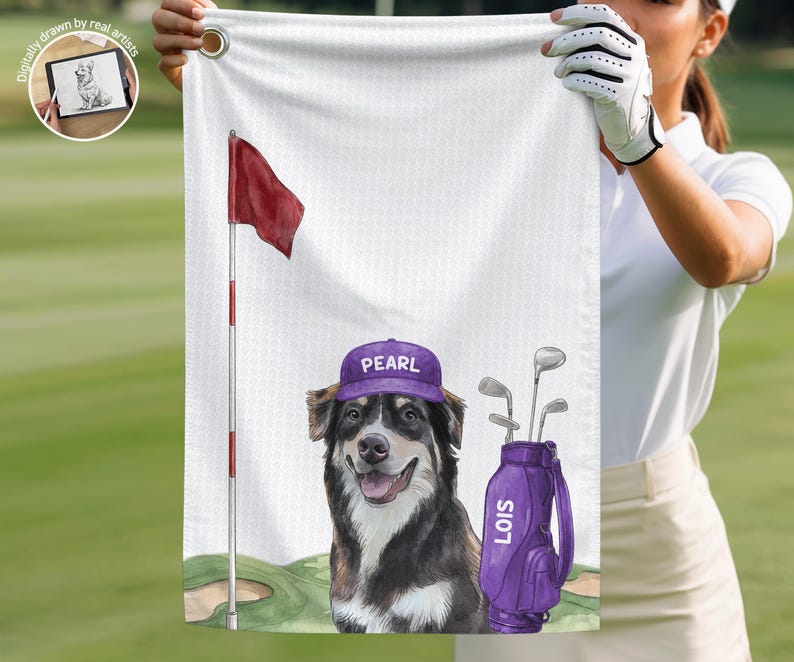 Op de afbeelding: Een witte golfhanddoek met een gedrukte illustratie van een hond die een paarse pet draagt met de naam PEARL, naast een paarse golf-tas met het label LOIS, een rode vlag aan een paal en een green op een witte, getextureerde achtergrond.