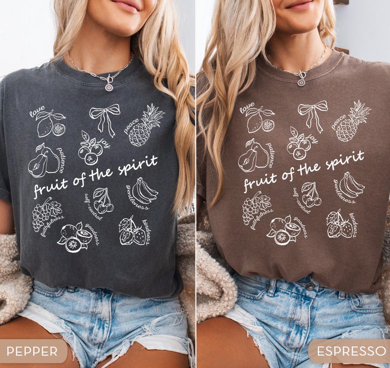 May include: Two t-shirts, one pepper-colored and one espresso-colored, each featuring a white graphic. The graphic includes the text "fruit of the spirit" and illustrations of various fruits and words like "love" and "peace".