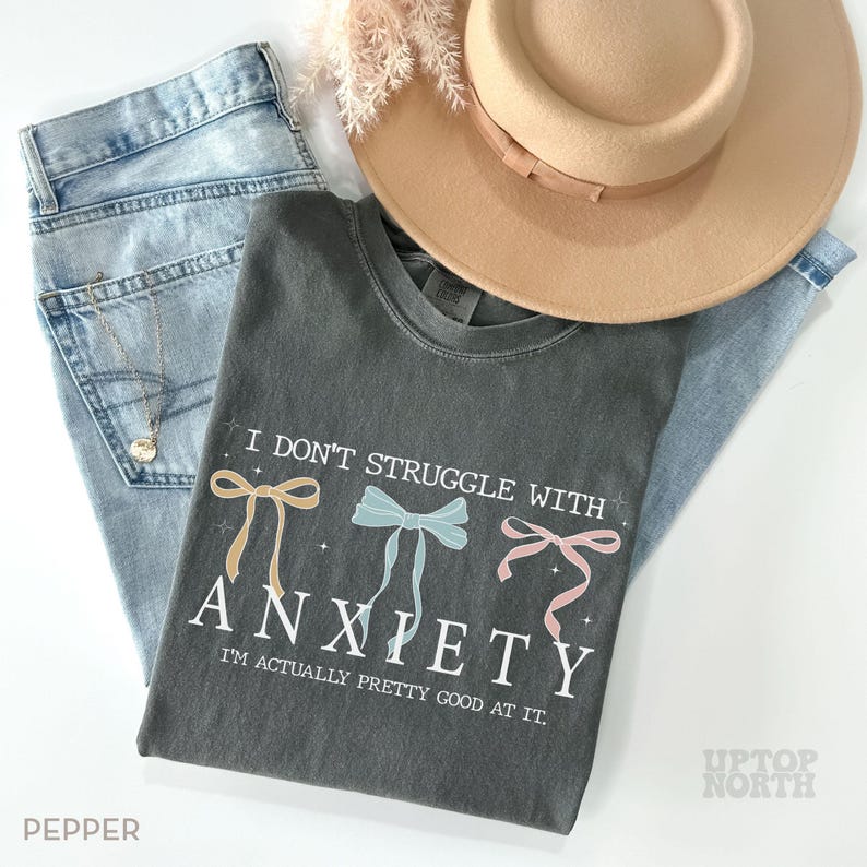 May include: A dark gray t-shirt with the text "I don't struggle with anxiety. I'm actually pretty good at it." and three colorful bows.