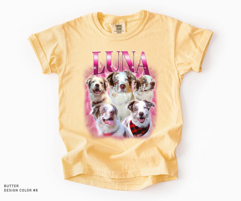 May include: A butter-colored short-sleeve t-shirt featuring a graphic print of five Australian Shepherd dogs. The word LUNA is printed in large, pink, gradient lettering above the dogs, which are set against a soft, pink, hazy background.