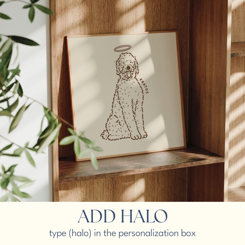 May include: A framed print featuring a doodle dog illustration with a halo. The dog is drawn in a simple, line art style with the name "KRATOS" on the side. The print is displayed on a wooden shelf, with the text "ADD HALO" below.