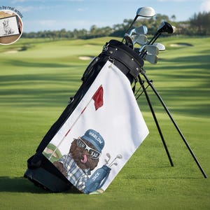 Op de afbeelding: Een zwarte golf-tas met een witte handdoek met een cartoonhond met een blauwe pet met de tekst Harlow, een zonnebril en een geruit overhemd, naast een golftas met de tekst Jack en een rode vlag. Een kleine cirkelvormige inzet toont een digitale tekening.