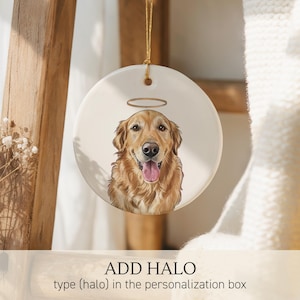 May include: A round white ceramic ornament featuring a detailed illustration of a golden retriever with a gold halo above its head. The dog has a happy expression with its tongue out. The ornament hangs from a thin gold string at the top.