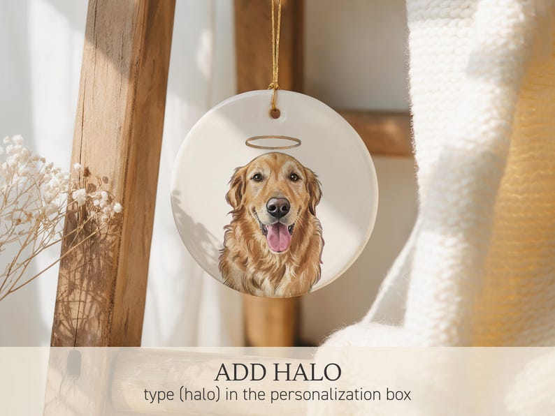 May include: A round white ceramic ornament featuring a detailed illustration of a golden retriever with a gold halo above its head. The dog has a happy expression with its tongue out. The ornament hangs from a thin gold string at the top.