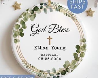 May include: White round ornament with a gold and green eucalyptus wreath design. The text reads "God Bless Ethan Young Baptized 08.25.2024".
