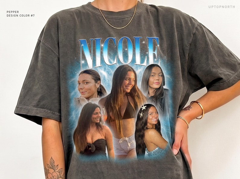 May include: A charcoal gray t-shirt featuring the name NICOLE in large blue letters at the top. Below the name, a collage of five photographs shows the same person in various settings. The text PEPPER DESIGN COLOR #7 and UPTOPNORTH are visible.