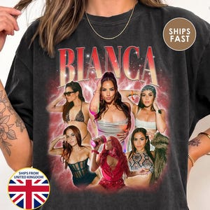 May include: A black short-sleeve t-shirt featuring a graphic print with the name BIANCA in large red and white letters. The design includes a collage of six photographs of a person in various outfits and poses, set against a red, hazy background with small white star accents.