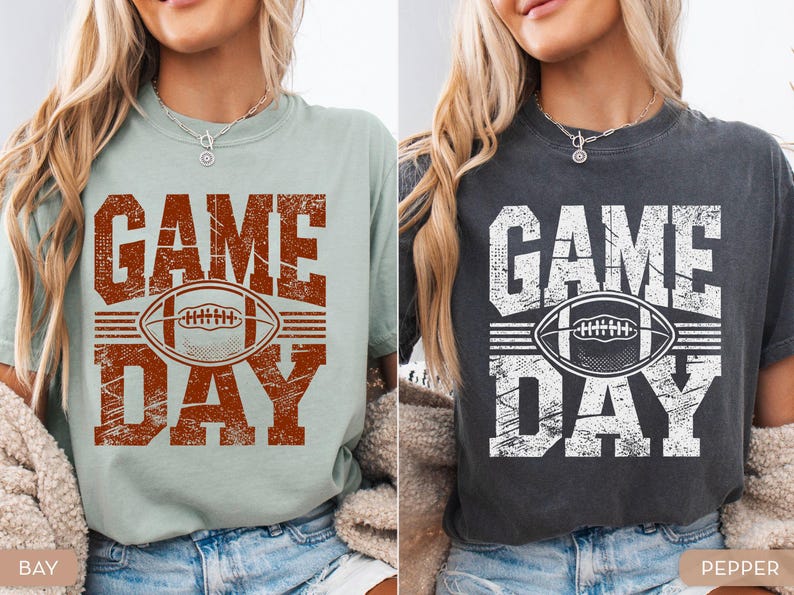 May include: Two t-shirts, one light green and one dark grey, each with a distressed "GAME DAY" design. The design includes a football graphic. The shirts are casual wear.